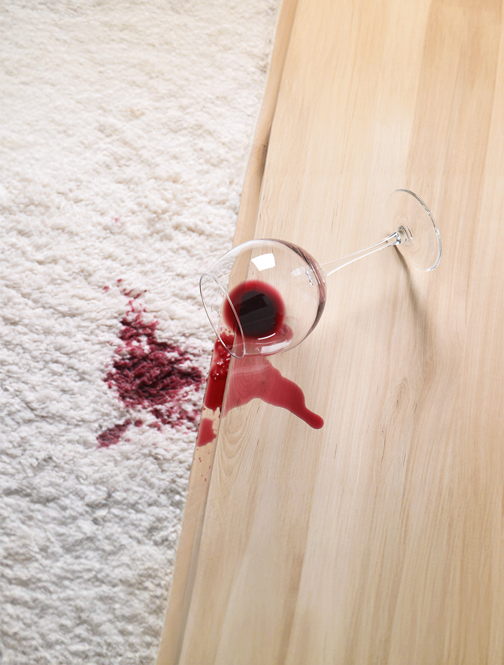 glass of red wine spilled on carpet and hardwood floor