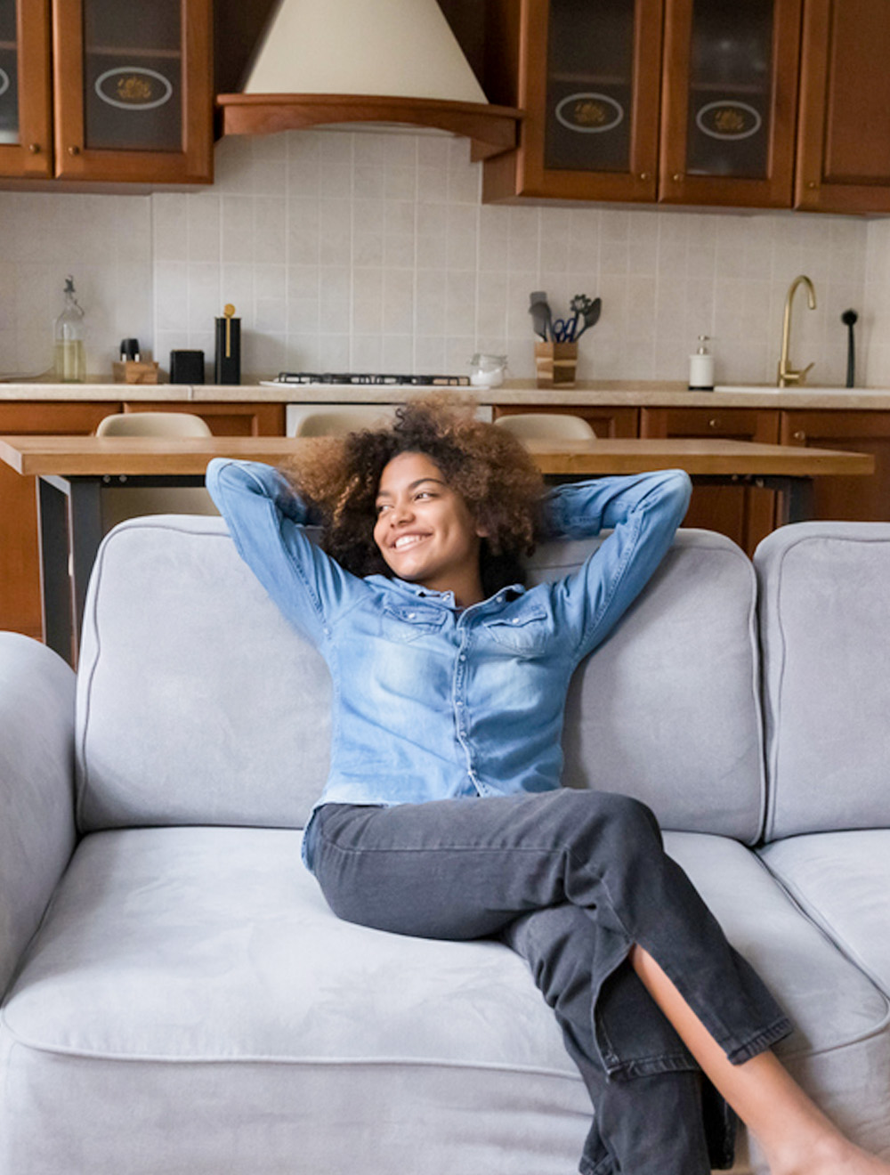 woman smiling and relaxing on couch inside freshly cleaned living room