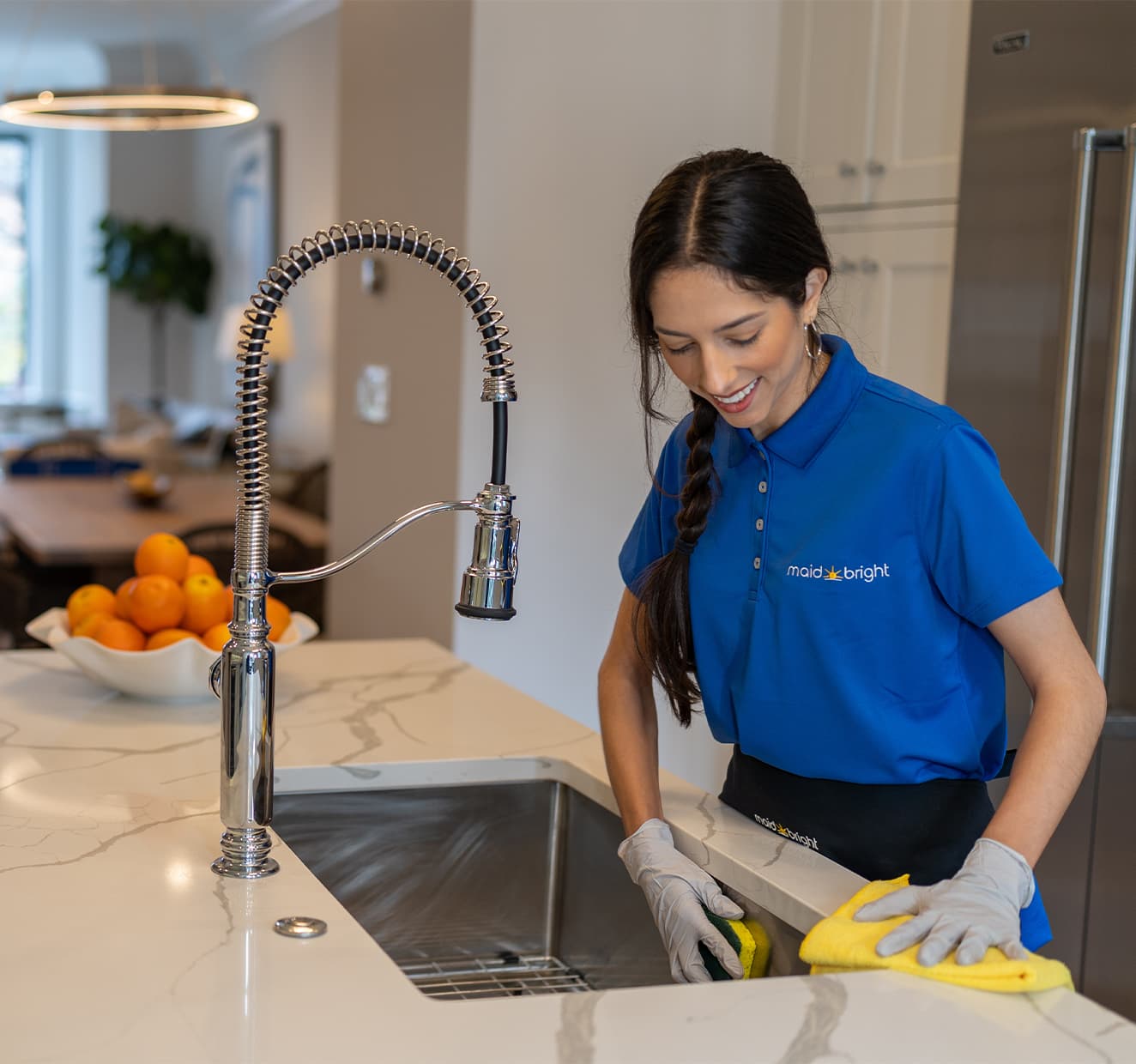 Professional house cleaner wiping a kitchen counter and sink