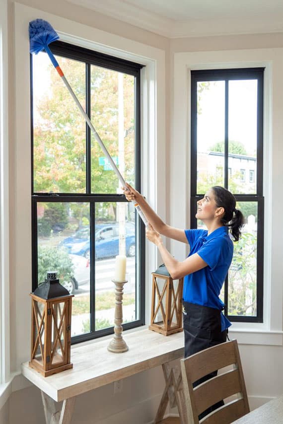 Maid Bright employee dusting around windows