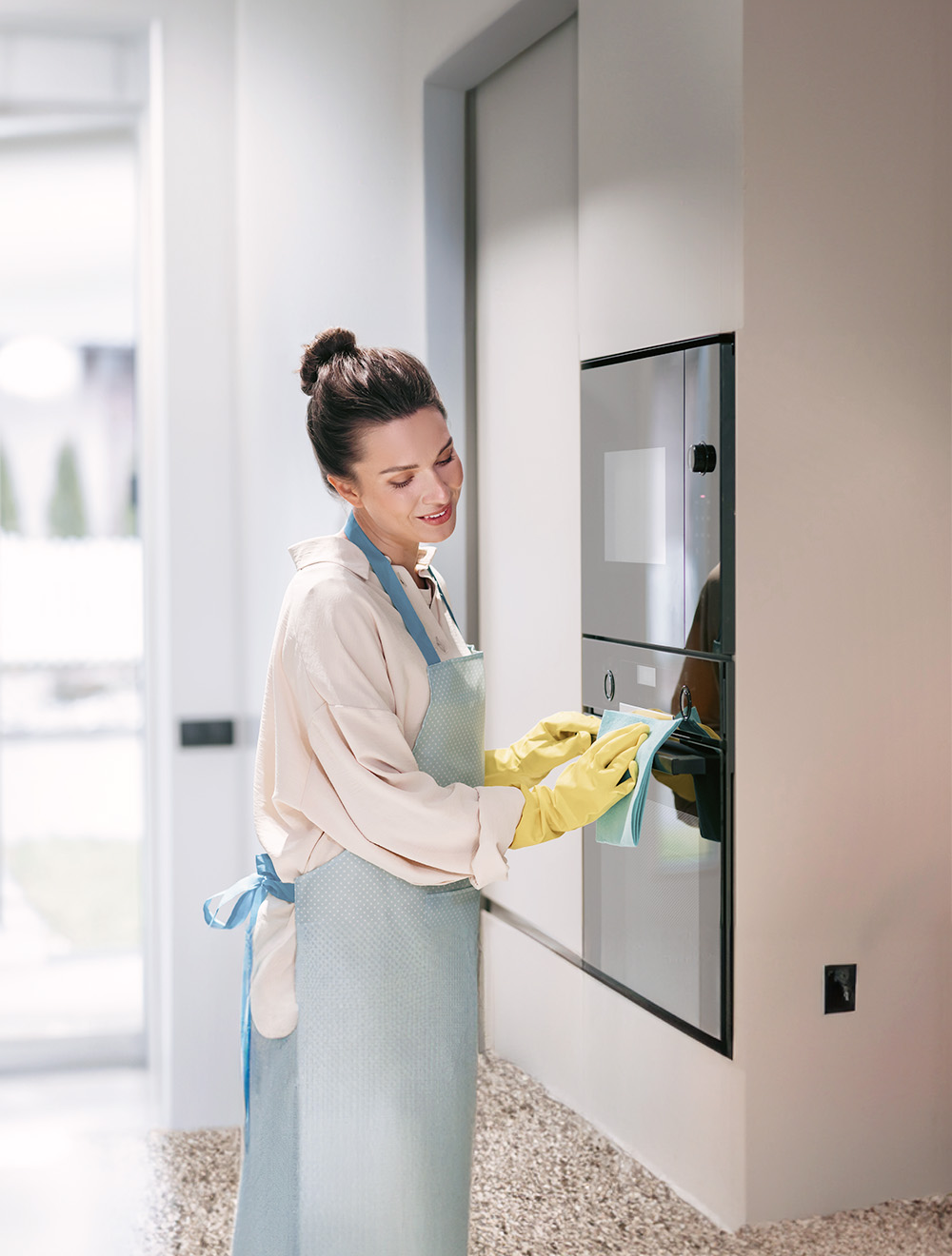 woman wearing gloves wiping down appliances