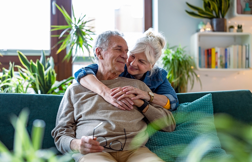 senior husband and wife sharing a hug on the couch
