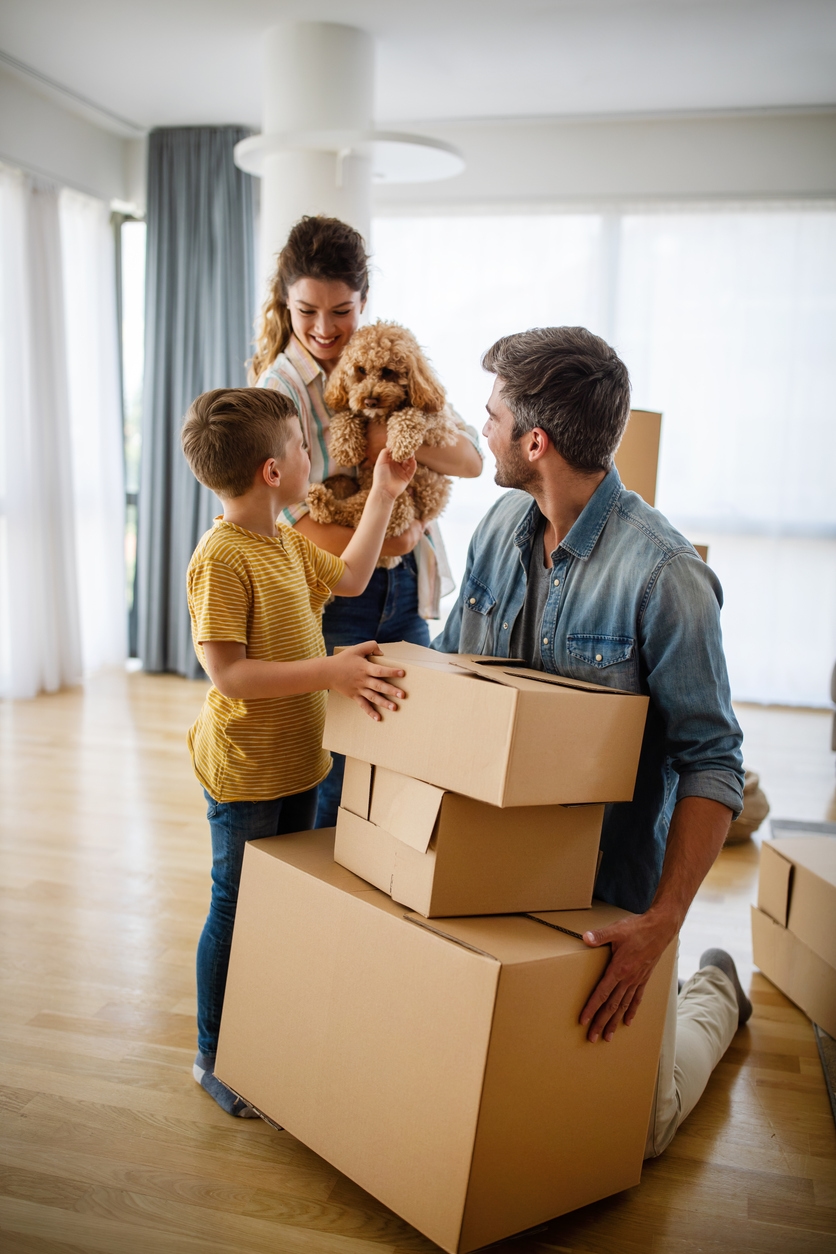 family standing next to moving boxes and mother holding a dog